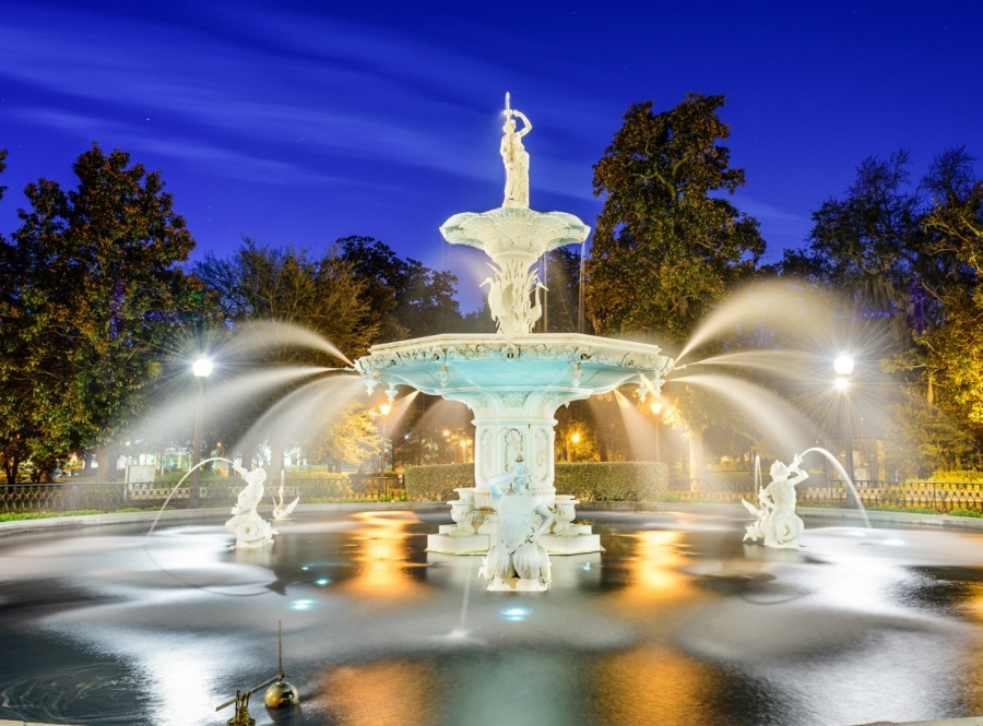 A fountain spouting water with trees and the night sky in the background